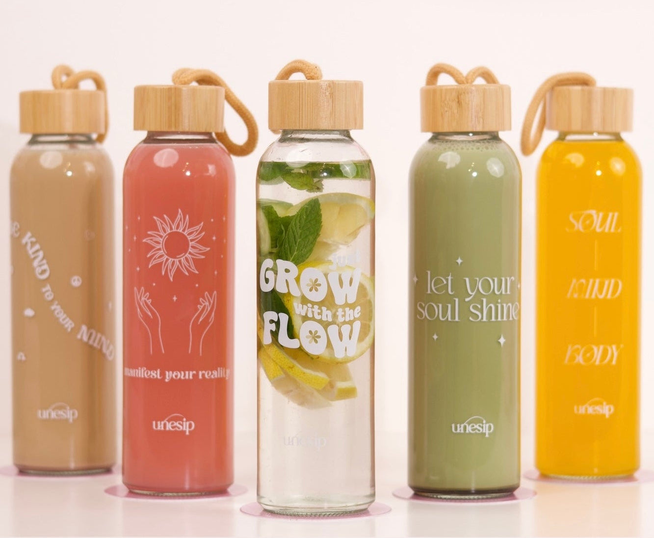 Five colorful water bottles with wooden caps on a white surface.