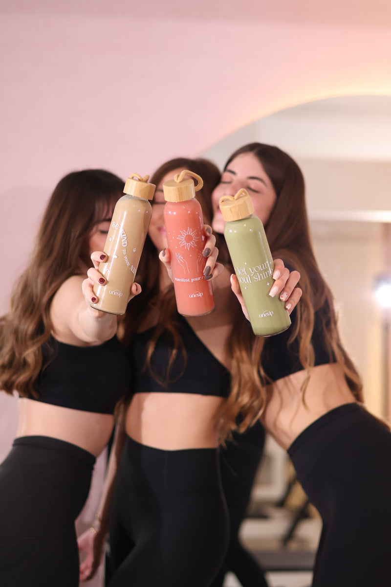 Three bottles of different colors held by a person with long hair.
